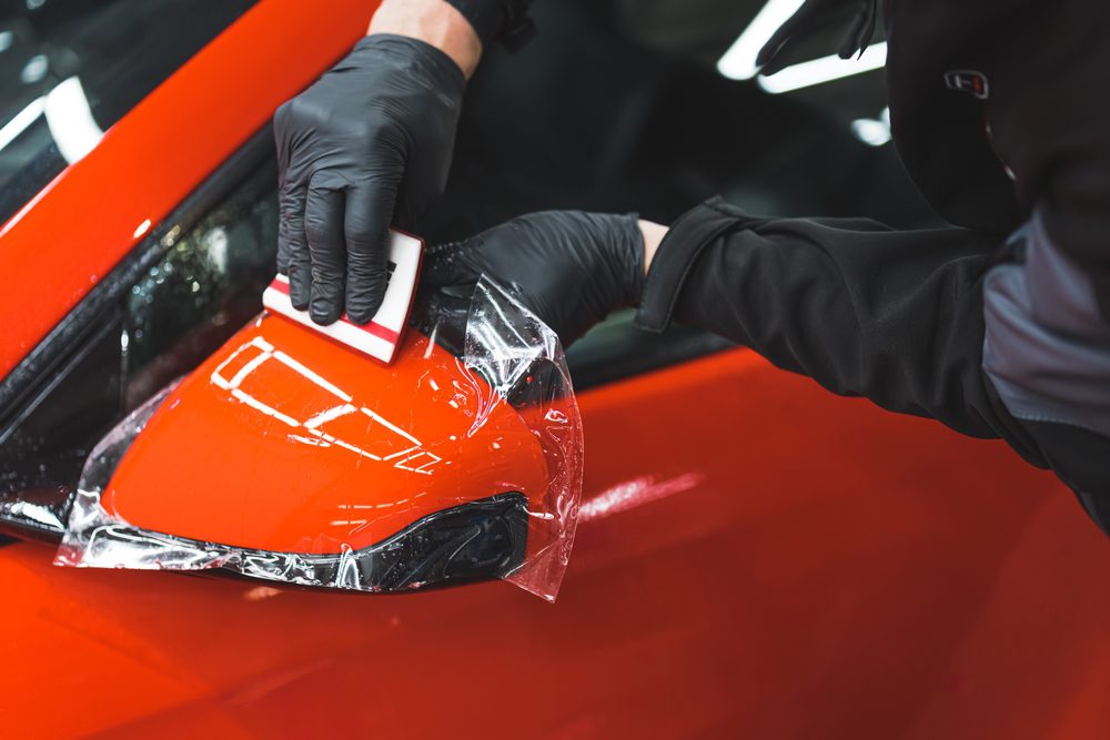 Hand with black gloves installing PPF